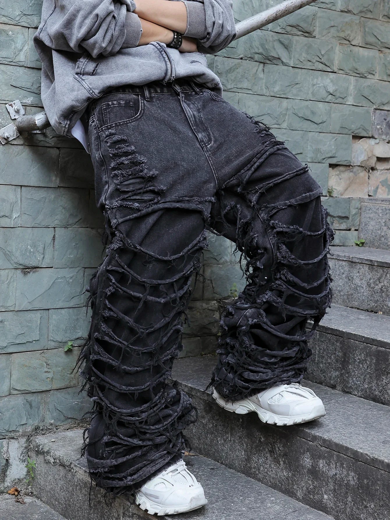Men's black jeans. With a design of (ripped holes) and tassels. In a street trend style.